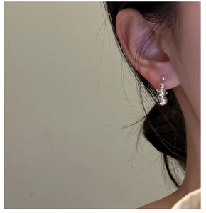 Close-up of three graduated silver beads earring on ear showing minimalist mirror polish