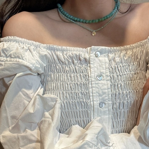 Detail of S925 silver double-layered necklace with green beads and gold round pendant