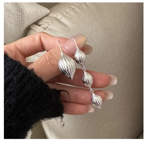Gros plan détaillé des boucles d'oreilles asymétriques en argent S925 au fini texturé