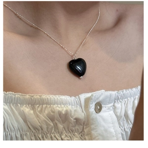 Close-up of black onyx heart pendant necklace on model's neck for elegant fashion look