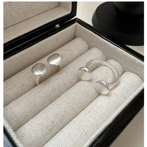 Detailed close-up of matte S925 sterling silver open rings on a beige linen cushion