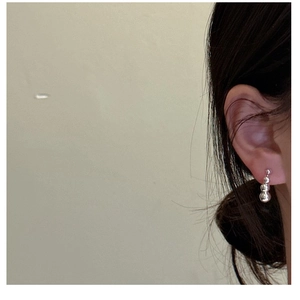 Close-up of 925 sterling silver drop earrings with three gradient polished beads on model
