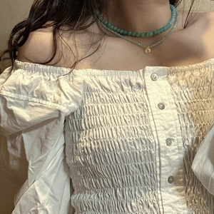 Detail of layered S925 silver necklace with mint beads and gold pendant on a model