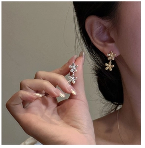 Dettaglio di orecchini a fiore in argento S925 in oro e argento indossati da una modella