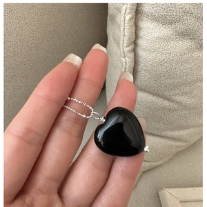 Detailed view of a black onyx heart pendant with a polished silver beaded chain