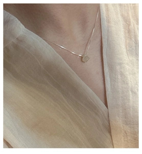 Detail of S925 silver necklace with minimalist natural stone pendant worn by model