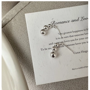 Macro shot of curved 925 sterling silver bead earrings on a minimalist display card
