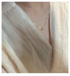Close-up of minimalist S925 sterling silver necklace with a pale green natural stone pendant