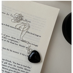Macro shot of black heart pendant on silver bead chain over an open book page