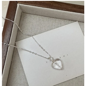 Dettaglio collana in argento S925 con ciondolo a cuore in cristallo su vassoio in legno