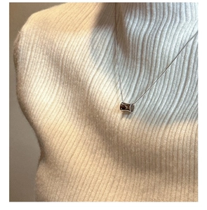 Detail of S925 sterling silver cylinder pendant necklace worn on a cream knit sweater