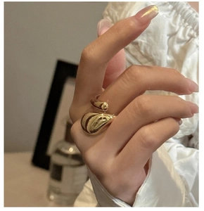 Gros plan d'une bague dorée minimaliste en forme de goutte d'eau portée par un mannequin
