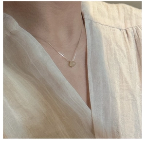 Detail of S925 silver necklace featuring an irregular light green translucent gemstone