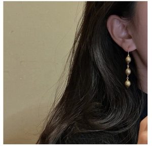Vue détaillée de longues boucles d'oreilles dorées à plusieurs niveaux sur modèle