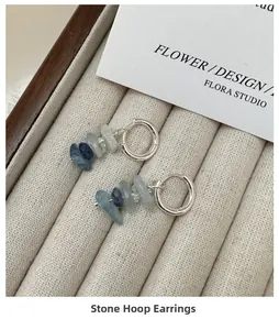 Detail of S925 silver hoop earrings with irregular blue stone pendants on beige velvet