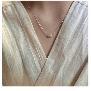 Close-up of minimalist S925 silver chain necklace featuring a pale yellow gemstone pendant