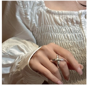 Detailed view of an S925 sterling silver minimalist X-shaped cross ring worn on finger