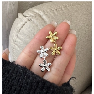 Dettaglio di orecchini a fiore in argento e oro con metallo spazzolato e petali