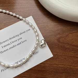 Collier en argent S925 minimaliste avec pendentif cœur et perles sur fond de bois