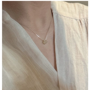 Close-up of minimalist S925 silver chain with irregular yellow gemstone on neckline