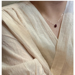 Close-up of a minimalist S925 silver necklace with a teardrop red gemstone pendant