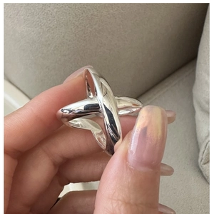 Close-up of a minimalist S925 sterling silver X-shaped crossover ring on a finger
