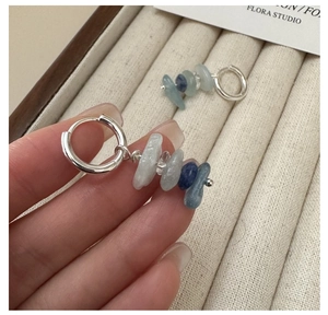 Detail of silver hoop earrings with irregular light and dark blue gemstone pendants