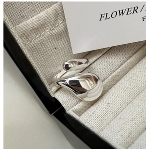 Détail macro d'une bague goutte d'argent sur un coussin en lin dans un écrin noir