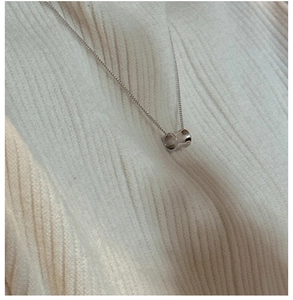 Detailed view of S925 silver cylinder necklace pendant on white knitted fabric