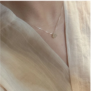 Close-up of minimalist S925 silver necklace with a pale green natural stone pendant