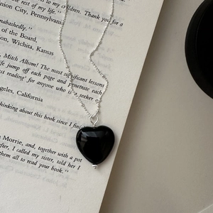 S925 silver heart necklace with black agate pendant on a vintage book page