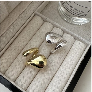Détail de bagues goutte d'eau or et argent avec texture métal liquide sur coffret beige