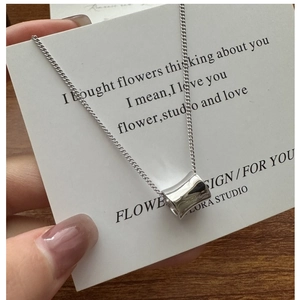 Close-up of polished S925 sterling silver cylinder pendant on a delicate chain necklace