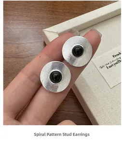 Detailed macro view of silver spiral stud earrings with elegant black onyx centers