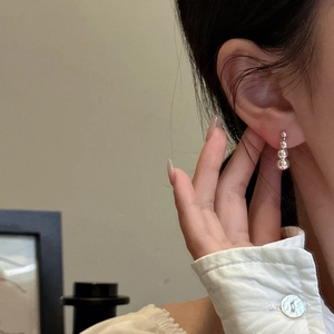 Minimalist 925 sterling silver triple bead drop earrings worn by a model in soft light
