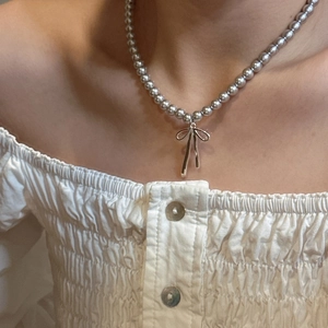 Close-up of S925 sterling silver beaded necklace featuring a sleek bow pendant on a model