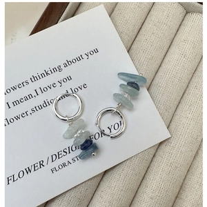 Macro detail of S925 silver earrings with natural irregular light blue and grey gemstones