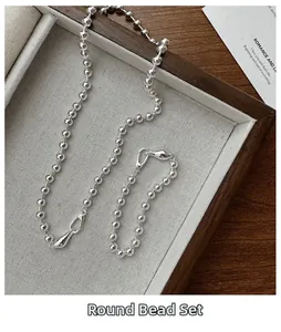 Detailed view of polished S925 silver ball chain necklace and bracelet set in a tray