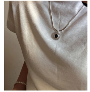 Detailed view of s925 silver necklace with black agate pendant and textured round design