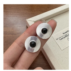 Detailed shot of silver textured round stud earrings with a black onyx center stone