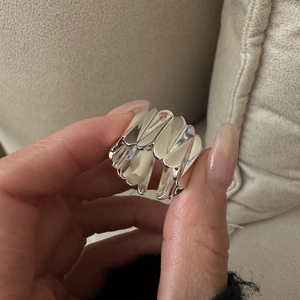 Gros plan sur la bague large en argent S925 avec texture géométrique et détails plissés