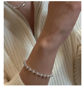 Close-up of minimalist polished silver bead bracelet worn on a wrist with sweater