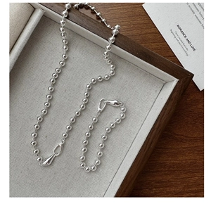 Detail of silver beaded ball chain necklace and bracelet set on linen display tray