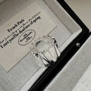 Bague large argentée aux lignes ondulées fluides présentée dans un écrin de luxe