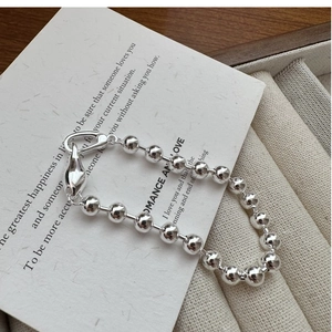 Macro shot of polished S925 silver beaded bracelet with unique teardrop clasp on card