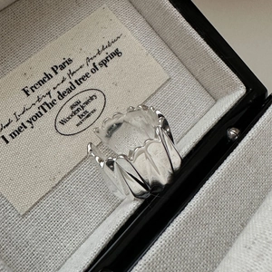 Détail d'une bague large en argent 925 avec bords dentelés dans un écrin de luxe élégant