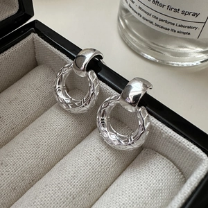Macro shot of silver hoop earrings with diamond pattern texture on a jewelry box