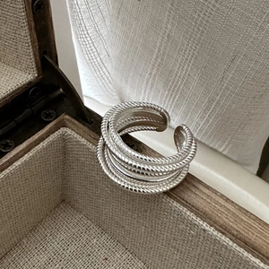Bague multicouche en argent S925 au design torsadé minimaliste sur une boîte en bois