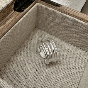 Vue macro d'une bague multicouche en argent S925 avec texture corde dans un coffret