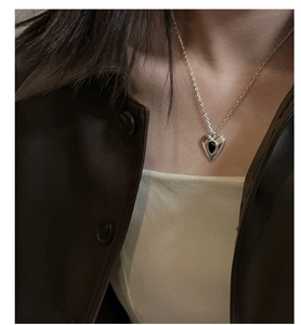Close-up of S925 silver heart necklace with black agate worn by model in chic outfit